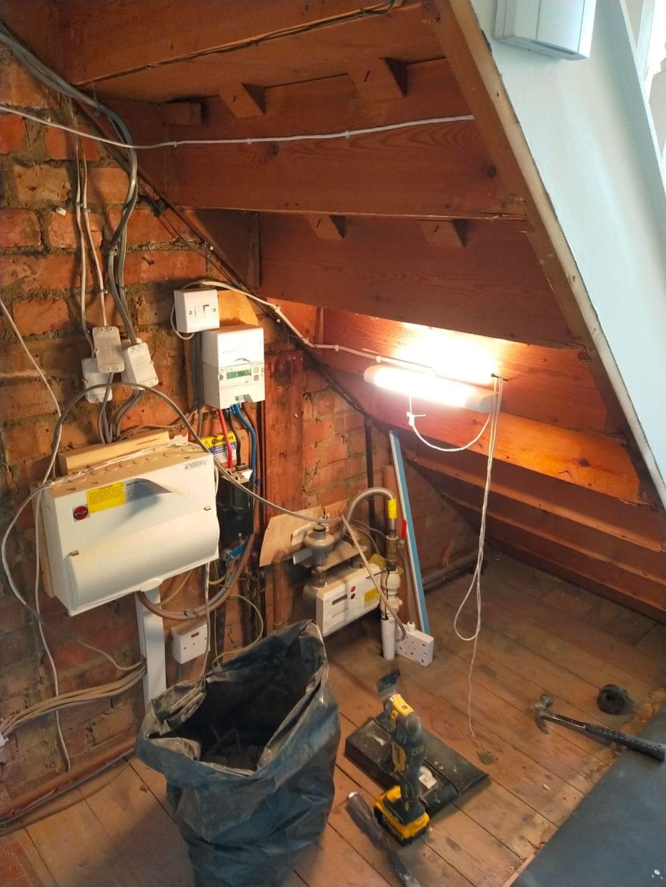 View inside an under stair cupboard showing multiple circuit boards, along with tools. 