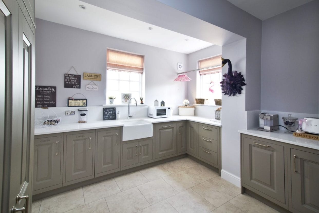Spacious utility room with sage shaker cabinetry, butler sink and white countertops.