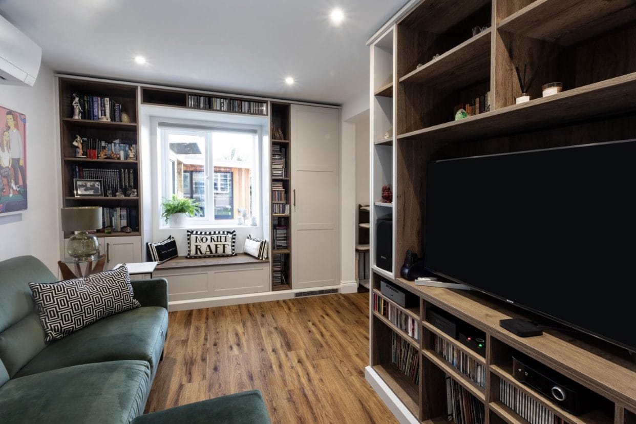 Opposite view of media room showing window seat storage surrounded by bespoke shelving.