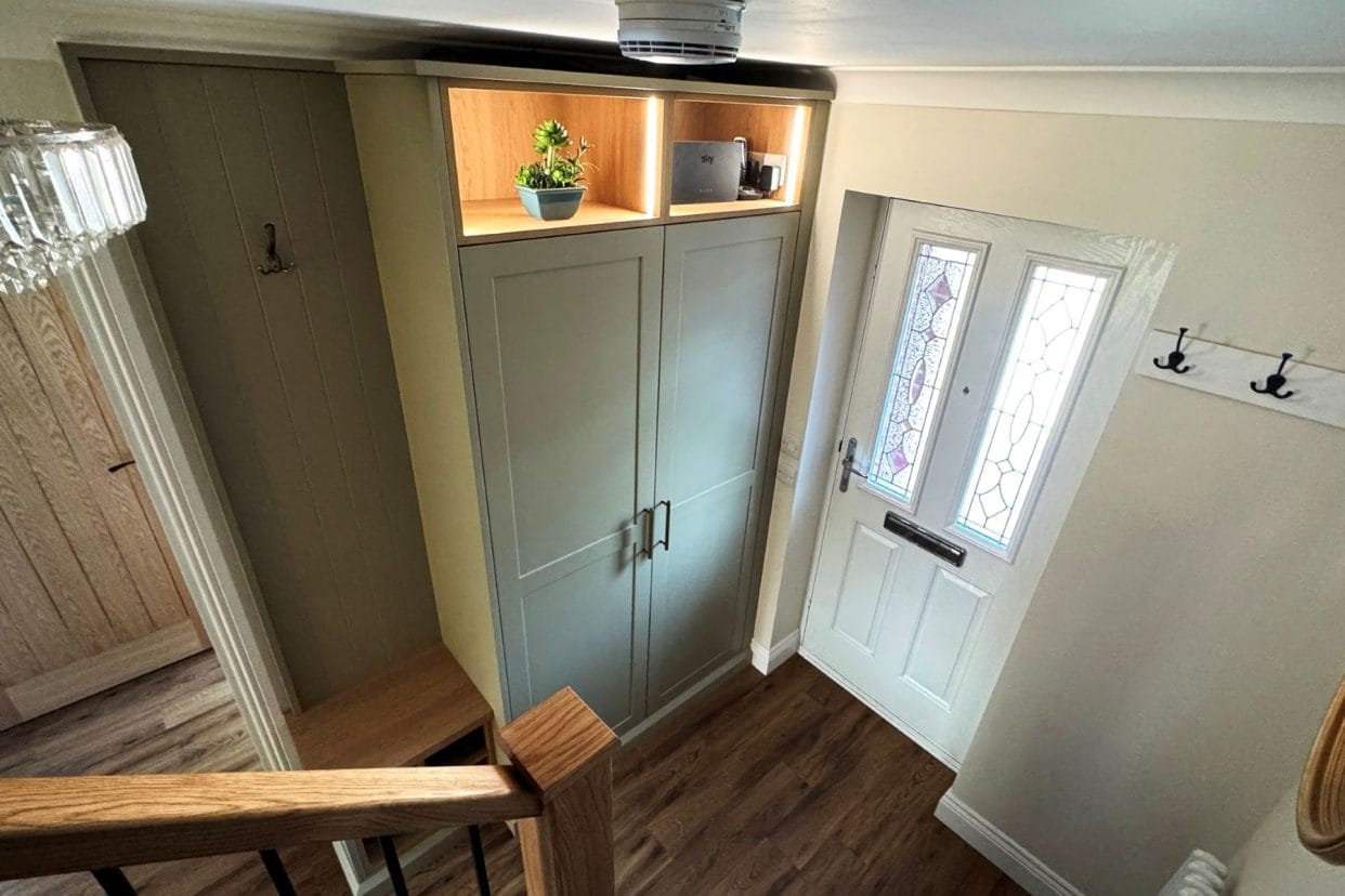 View of full height double cupboard and built-in seat which are both next to the front door, taken from halfway up the stairs.