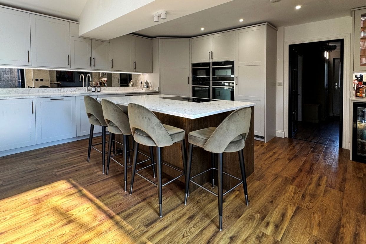 Reverse view of the kitchen showing the seating round the kitchen island and demonstrating the mirrored splashback.
