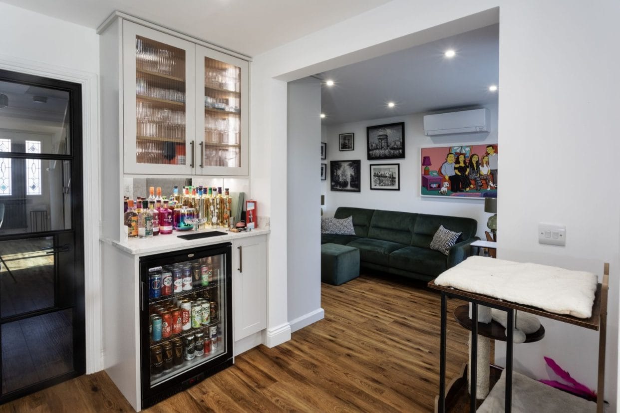 A view from the kitchen into the living space beyond showcasing the dresser-style cabinetry used for a home bar incorporating a wine fridge.