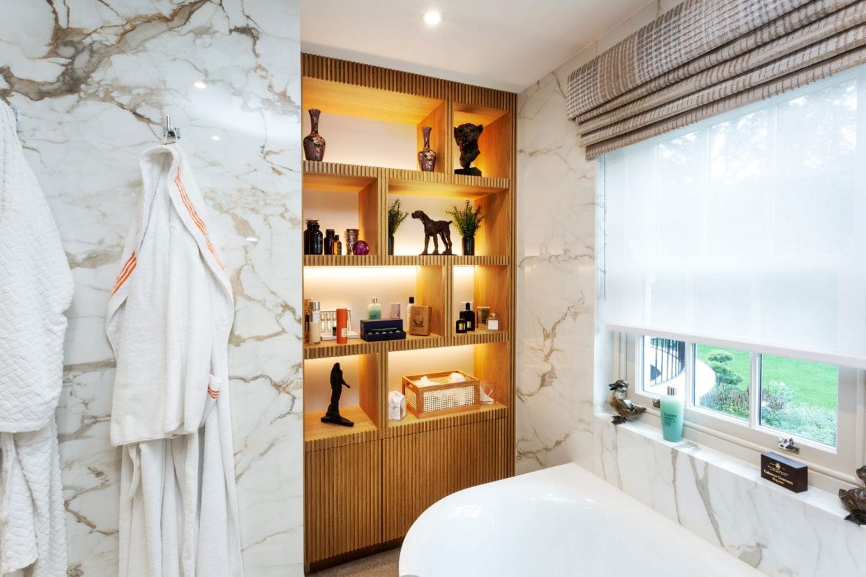 A stylish Scandinavian style bathroom with marble-effect wall panelling and full-height cabinetry finished in a slimline slatted design.
