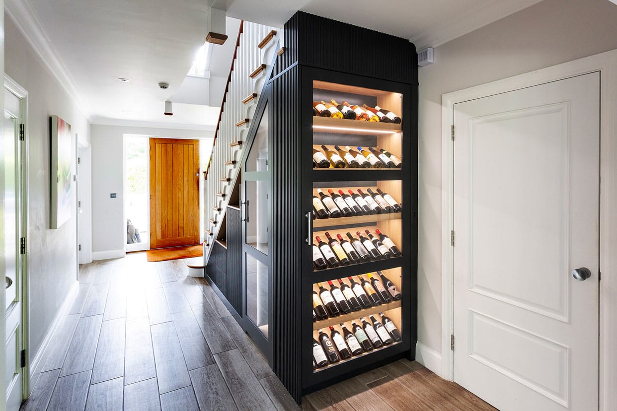 A light hallway with innovative under stair wine storage in a black slatted design.