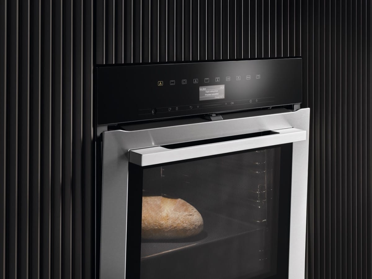A sleek Miele oven with a loaf of handmade bread baking inside.