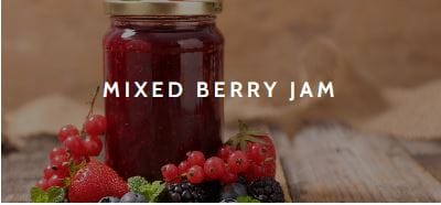 A jar of jam with fresh red currents, strawberries and blackberries.