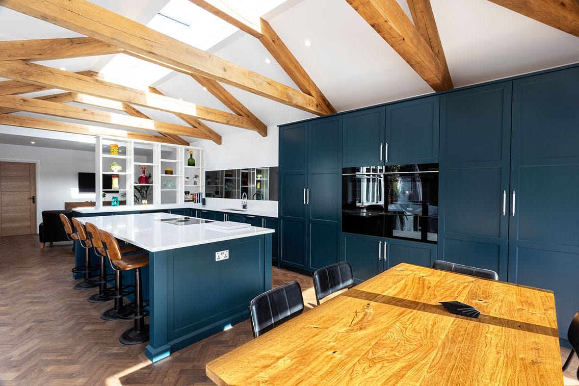A beautiful deep teal-painted handmade shaker kitchen, set within a vaulted space with oak beams.