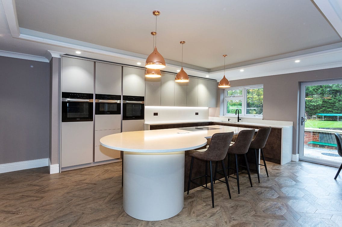 A bright contemporary kitchen with flat panel doors and a central feature island with a curved drum shape at one end.