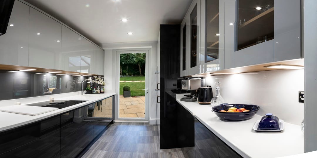 Panoramic view of a galley kitchen in black and white – with gloss white and black acrylic flat panel doors and quartz worktops