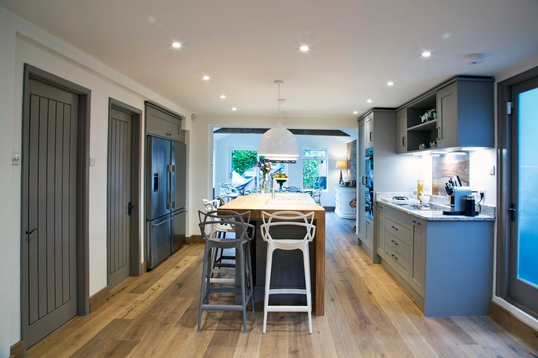 A spacious, shaker galley-style kitchen with a central island with seating and modern pendant lights