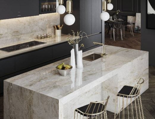 Dekton Stonika Taga demonstrated on both an island with waterfall edge, a splashback and countertop. The subtle natural markings within a rich cream background are paired with black cabinetry.