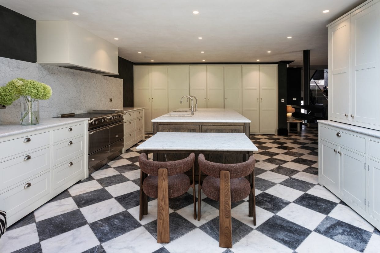 View of a modern shaker kitchen towards the wall of cabinetry, showing the overmantel to the left over the range cooker.